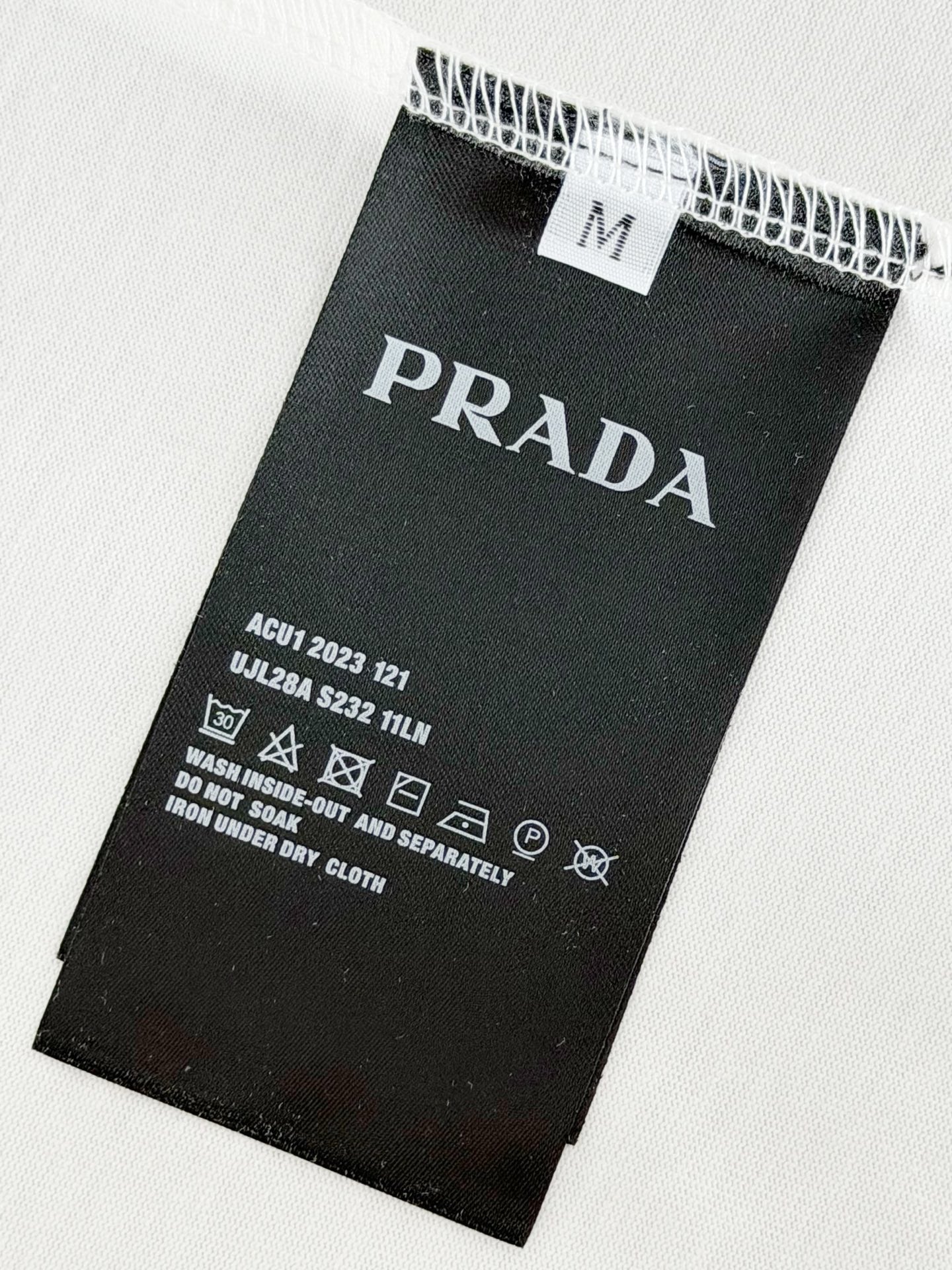 Black care label on white T-shirt fabric with Prada Milano details