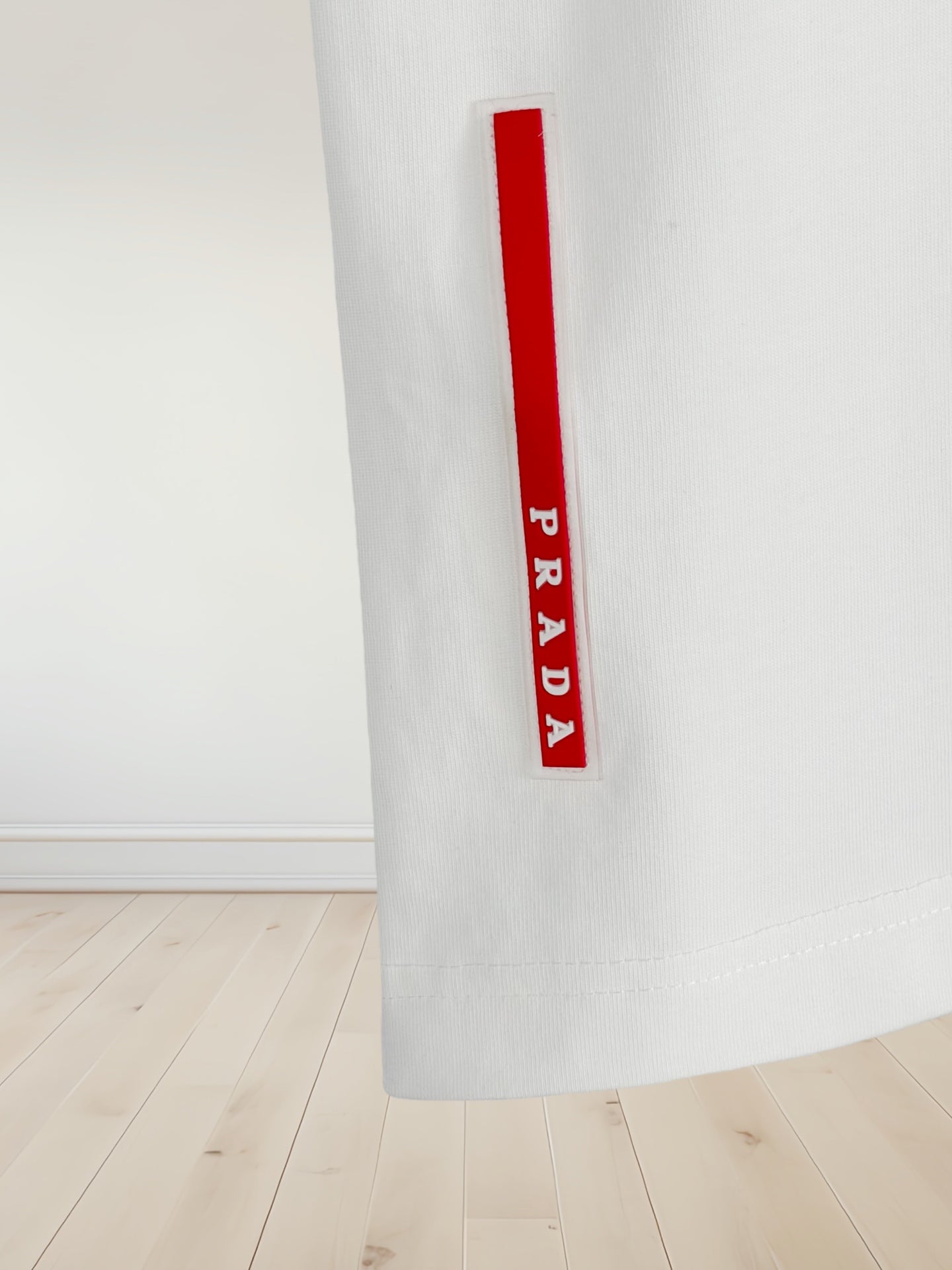 White T-shirt sleeve with red Prada label text