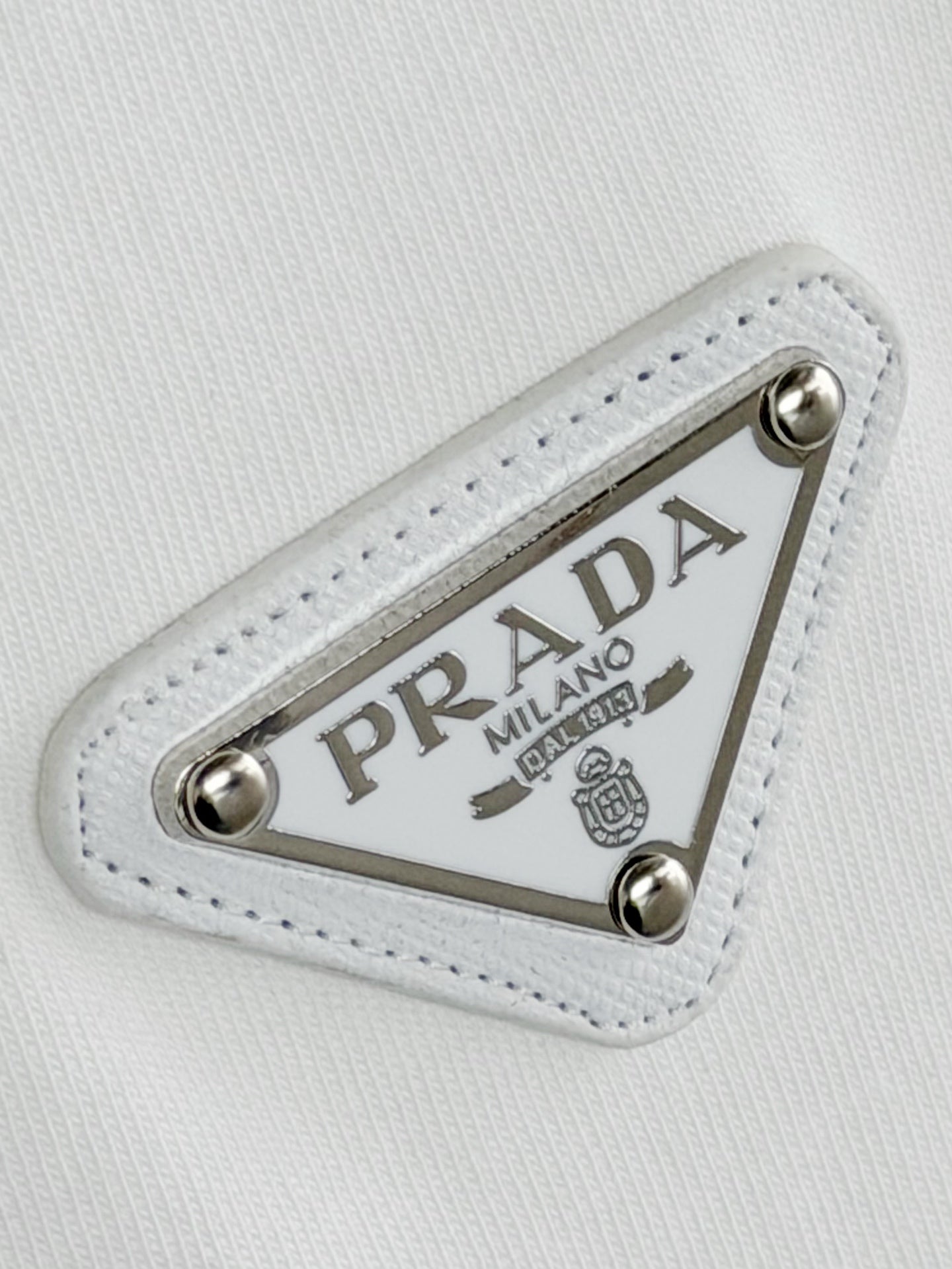 Prada Milano logo patch detail on white fabric with silver studs