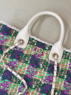 Chanel tweed handbag close-up, multicolor textured fabric with white leather trim and chain