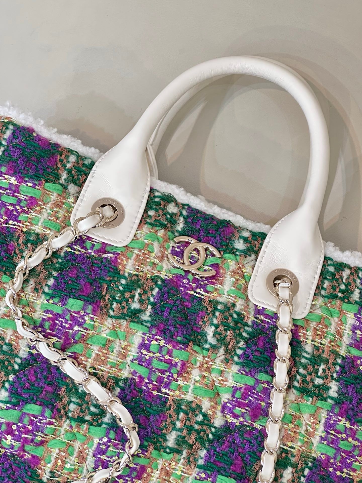 Chanel tweed handbag close-up, multicolor textured fabric with white leather trim and chain