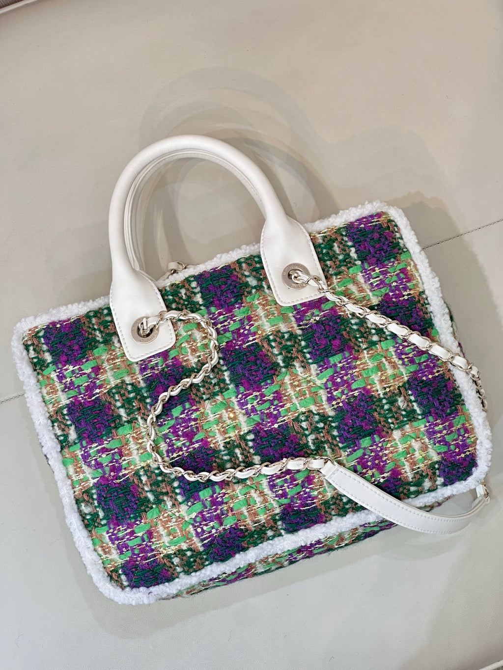 Chanel tweed handbag three-quarter view, white handle straps, multicolor textured panel