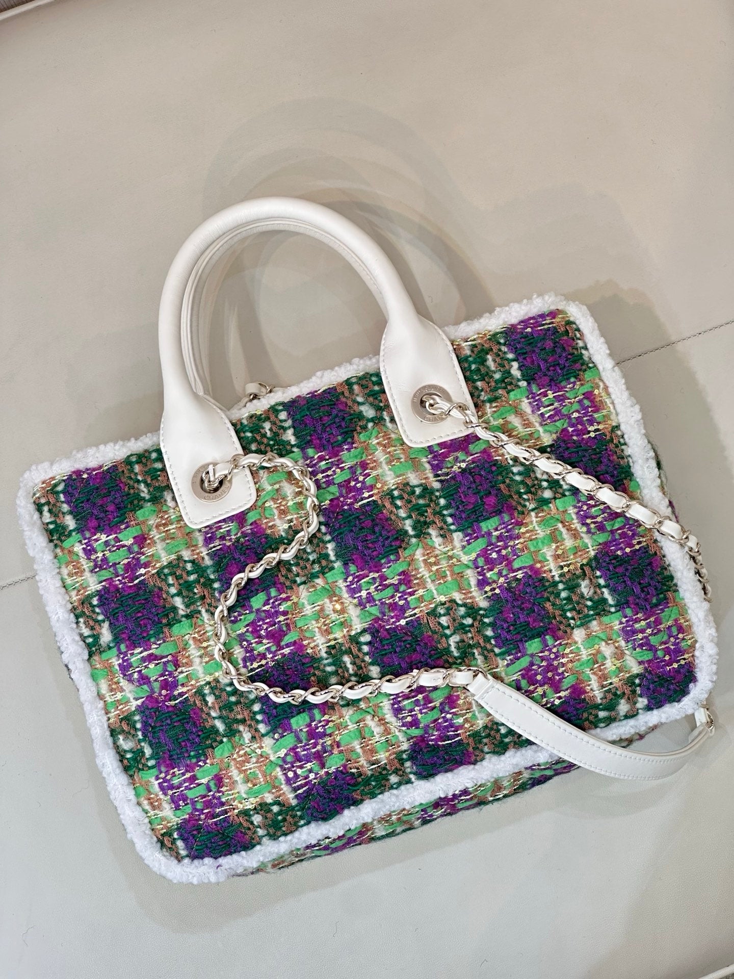 Chanel tweed handbag three-quarter view, white handle straps, multicolor textured panel