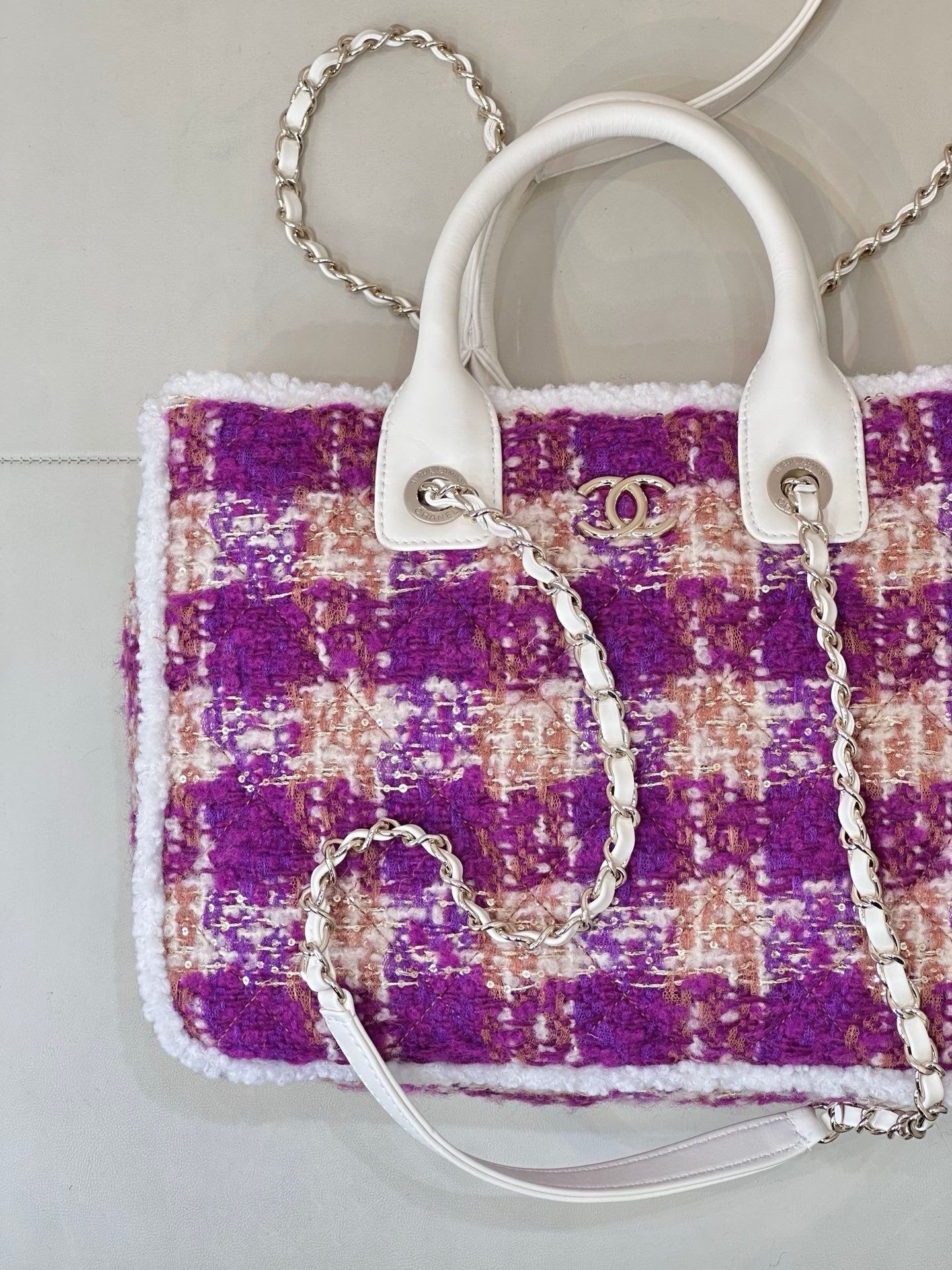 Chanel bag showing logo emblem on white tabs, purple tweed with silver chain