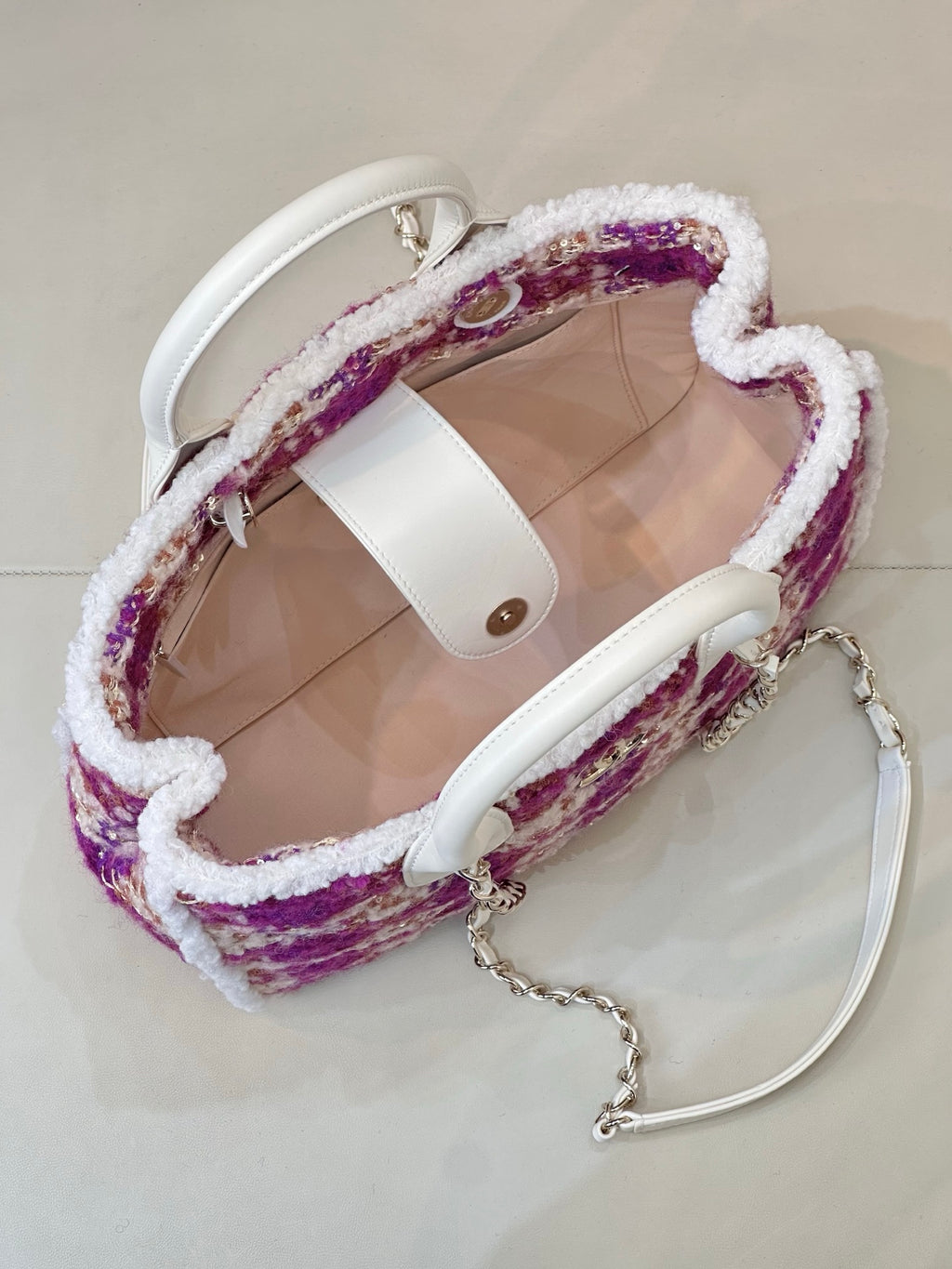 Chanel bag open view with beige interior, white handles, and purple tweed exterior
