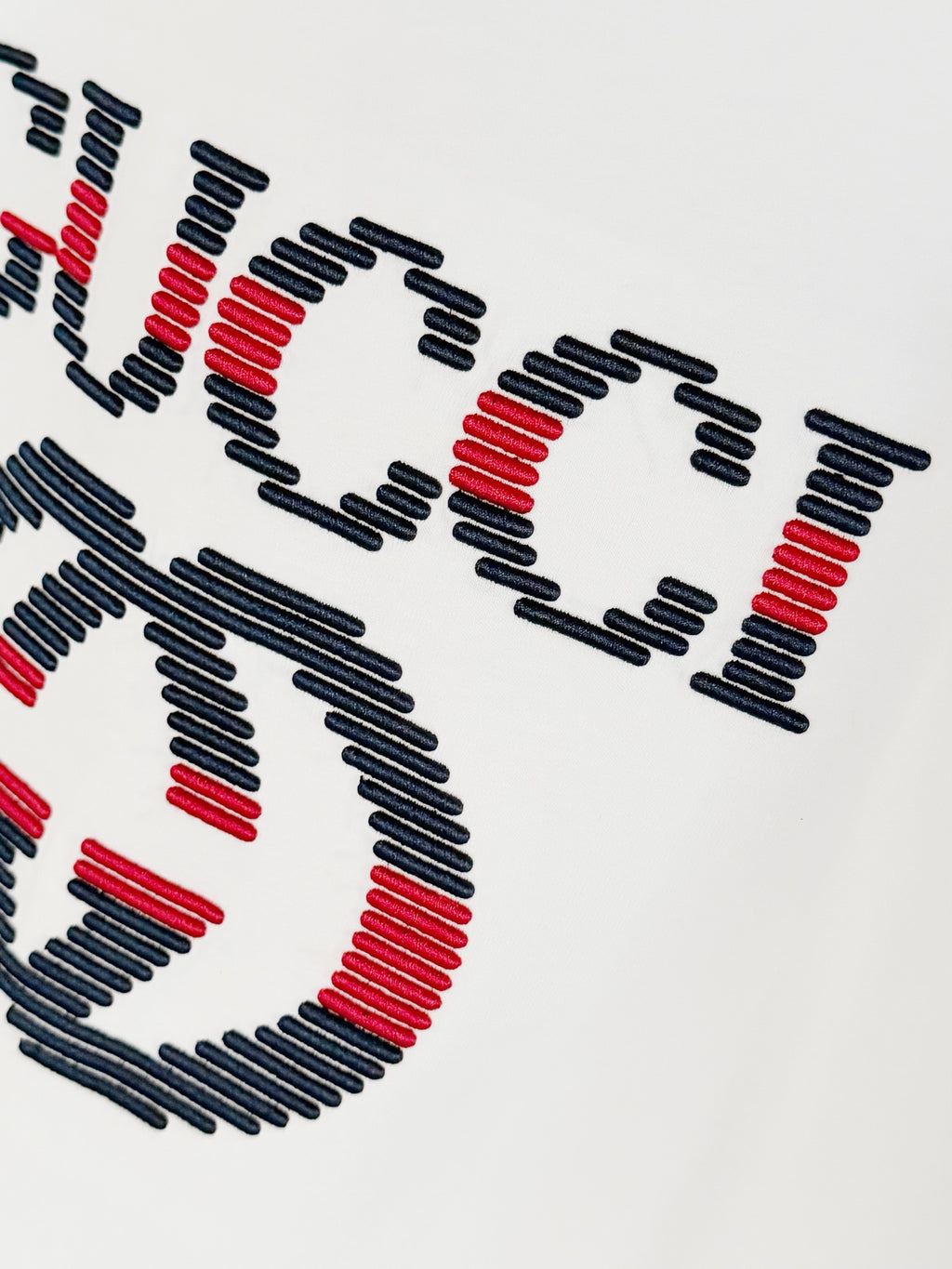 White T-shirt chest embroidered Gucci logo, angled close-up
