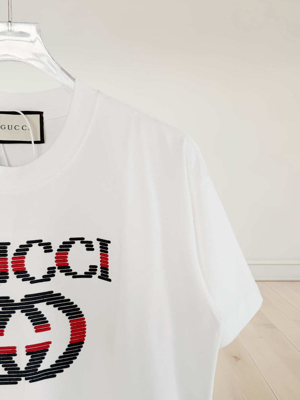 White T-shirt sleeve with partial multicolor Gucci logo embroidery