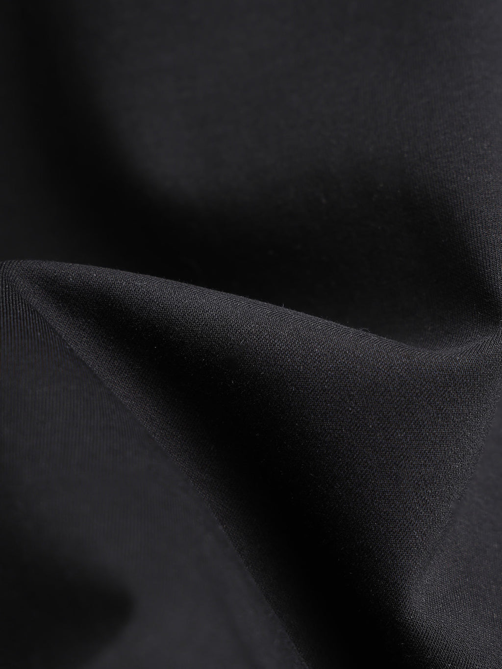 Black T-shirt fabric close-up with sleeve fold texture