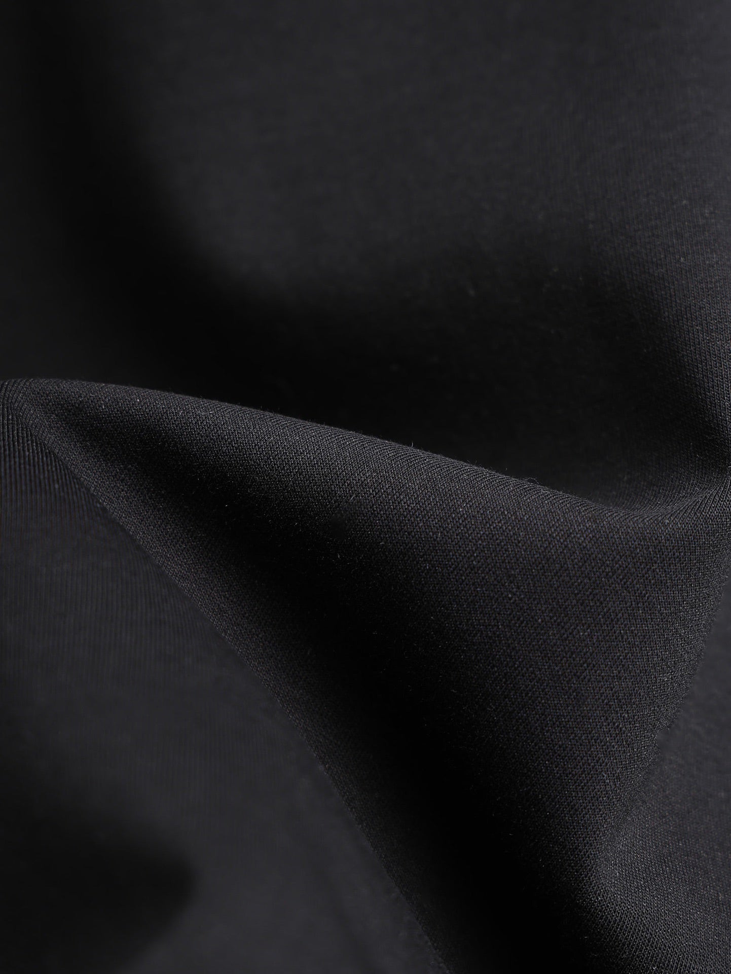 Black T-shirt fabric close-up with sleeve fold texture