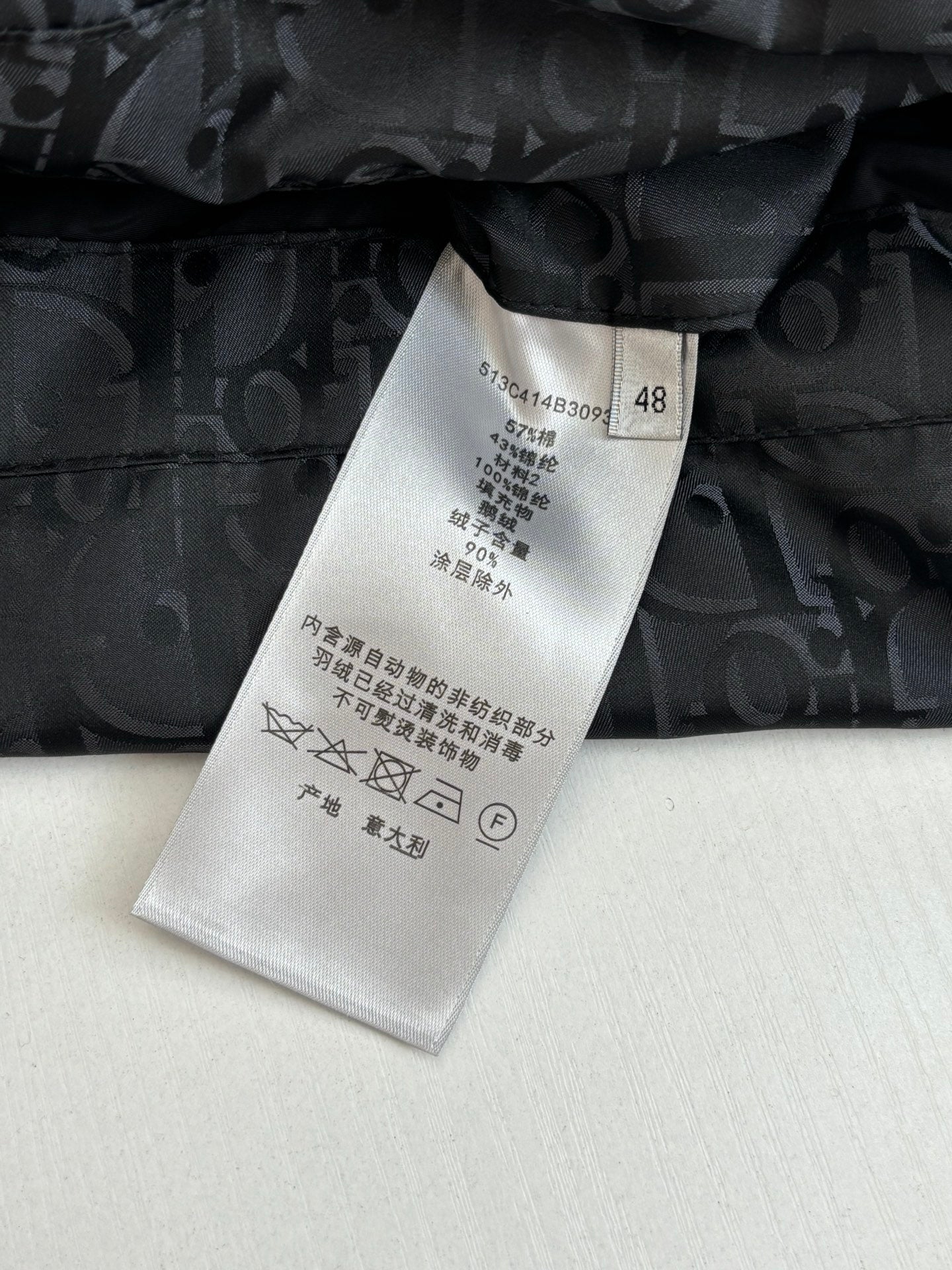Clothing care label on dark quilted Dior monogram jacket with black button
