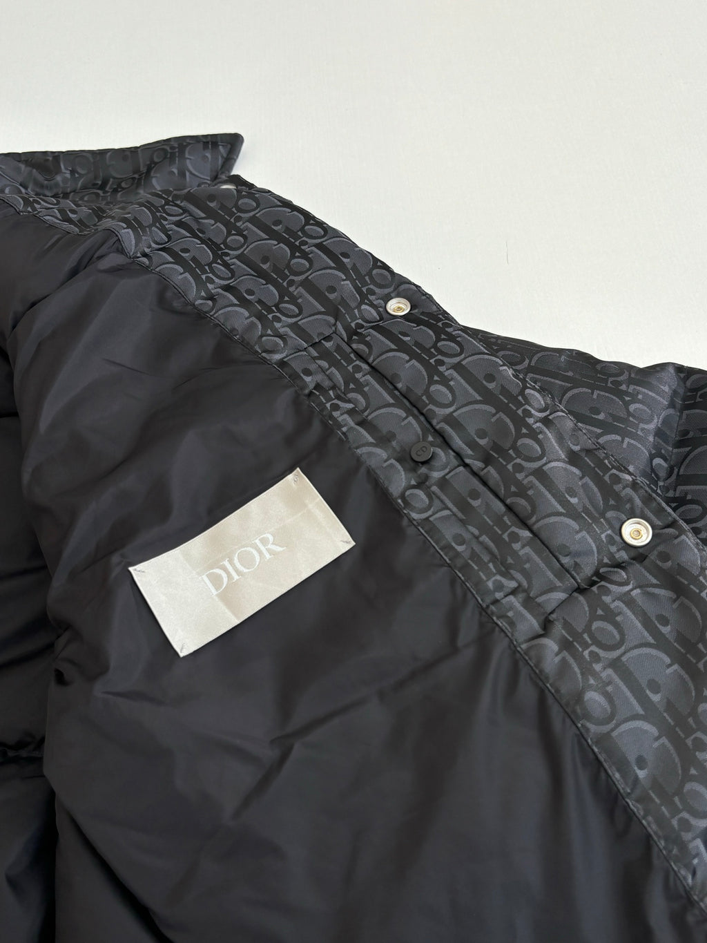 Dior long puffer jacket, dark navy, side close-up with gold snap buttons