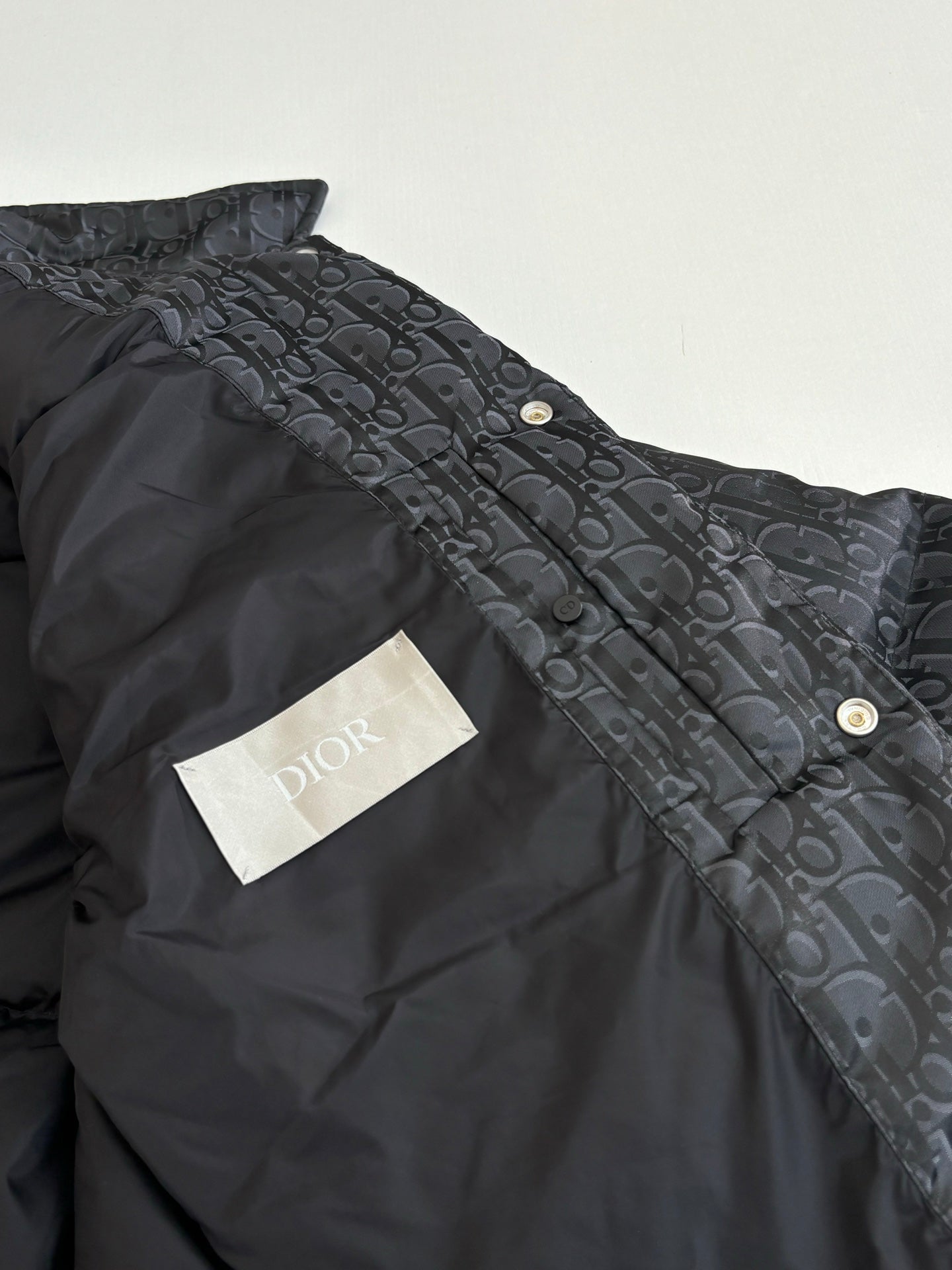 Dior long puffer jacket, dark navy, side close-up with gold snap buttons