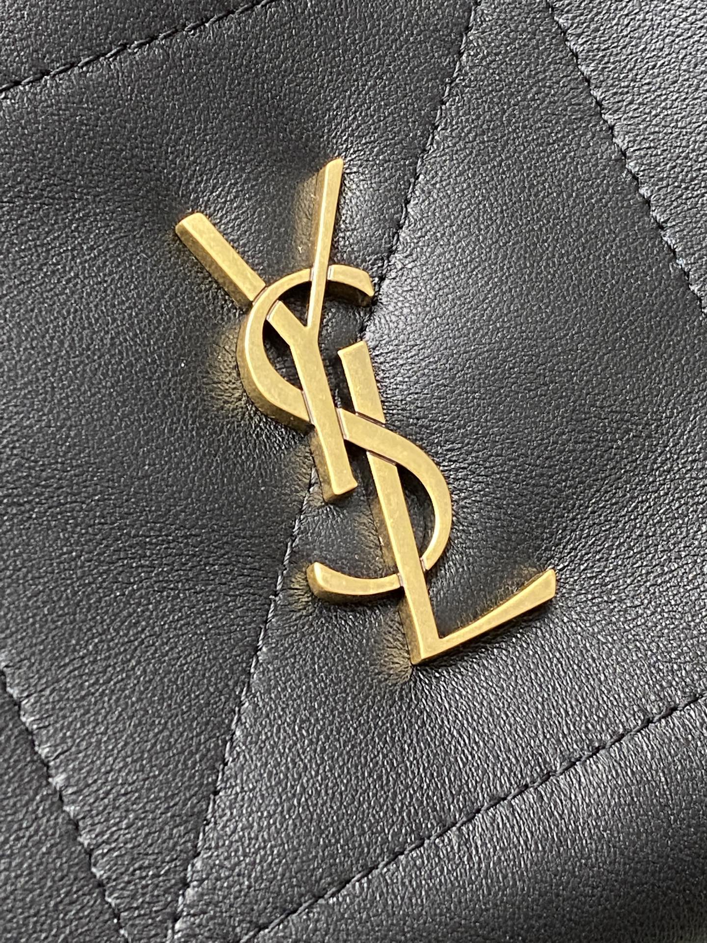 Gold YSL monogram on quilted black leather bag panel