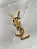 YSL bag close-up of gold YSL monogram on white quilted leather