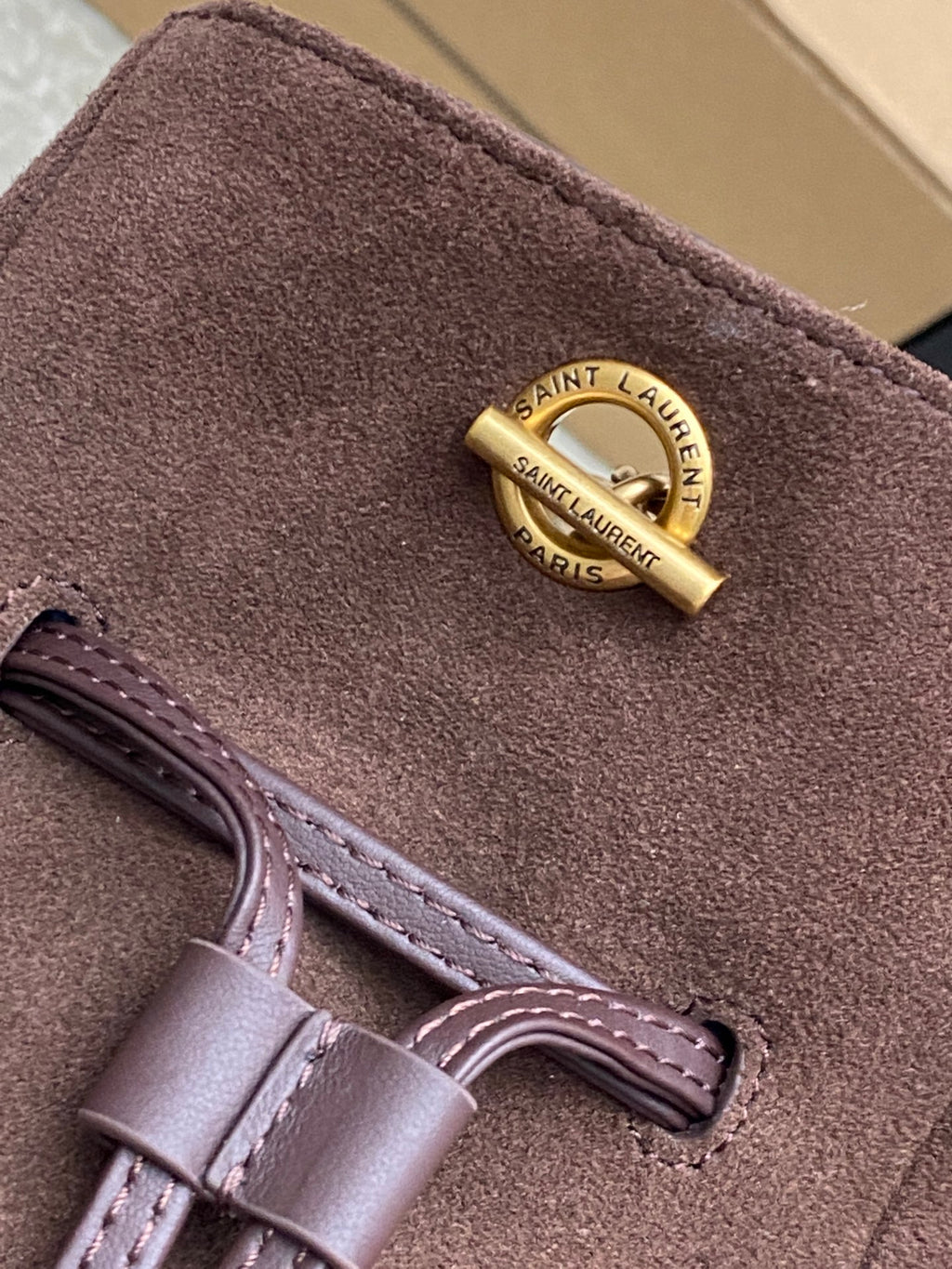 YSL bag suede close-up with gold Saint Laurent Paris tag and leather strap
