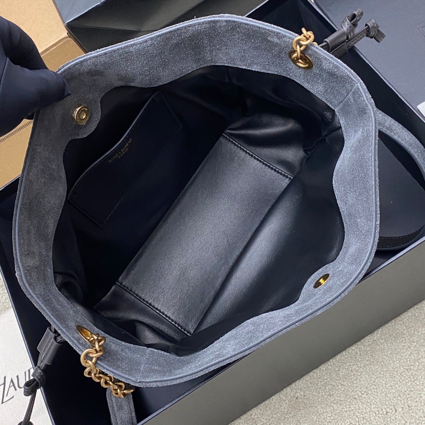 Blue-gray suede YSL bag open to reveal black leather interior and pocket