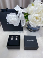 Jewelry set presentation with black box and silver-tone logo stud earrings inside.