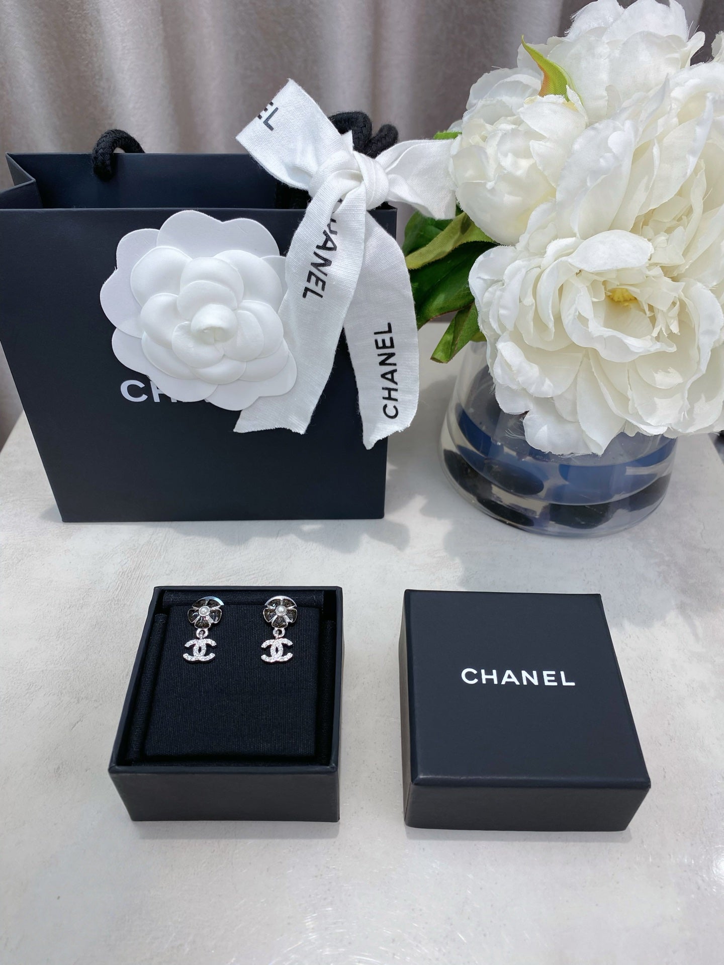 Jewelry set presentation with black box and silver-tone logo stud earrings inside.