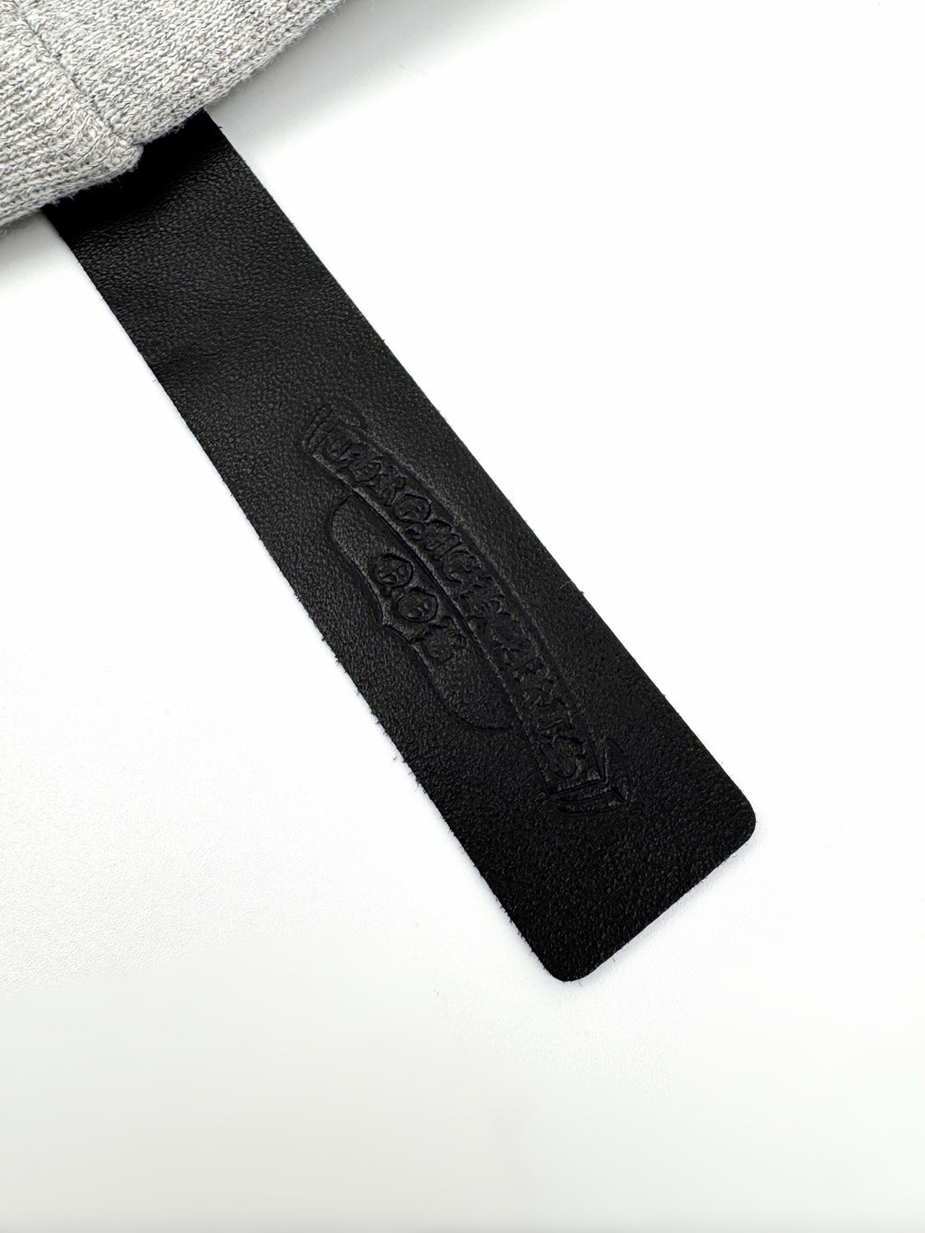 Black fabric neck label with embossed brand text on gray hoodie.