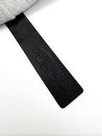 Black fabric neck label with embossed brand text on gray hoodie.
