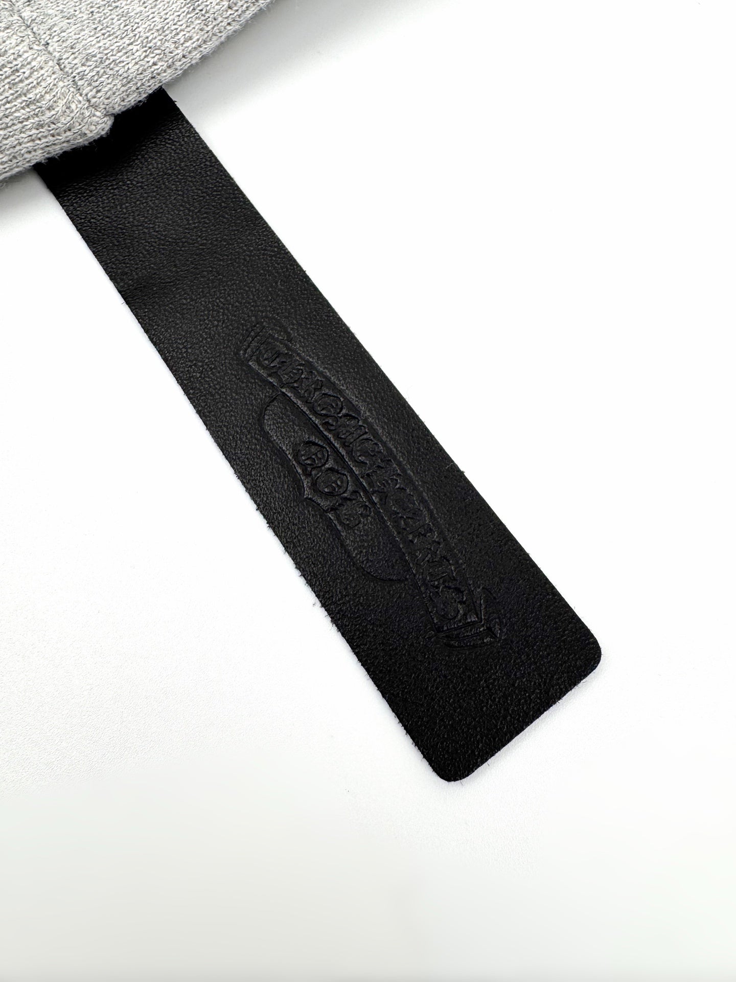 Black fabric neck label with embossed brand text on gray hoodie.