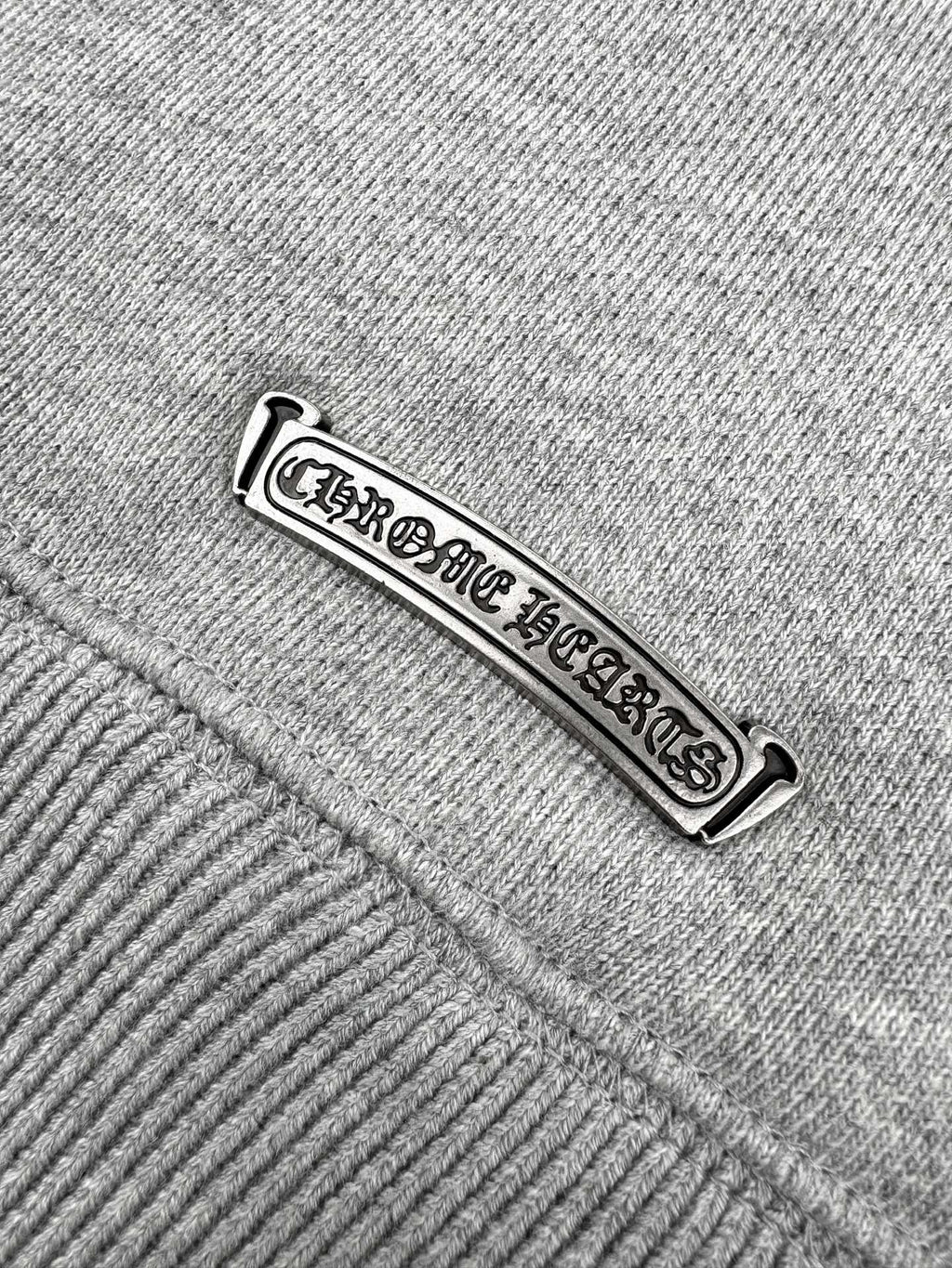 Gray hoodie tag close-up with embossed brand lettering.