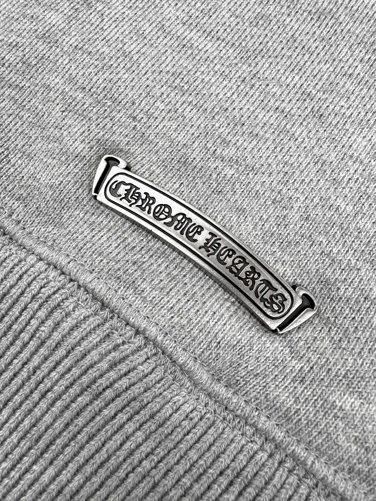 Gray hoodie tag close-up with embossed brand lettering.