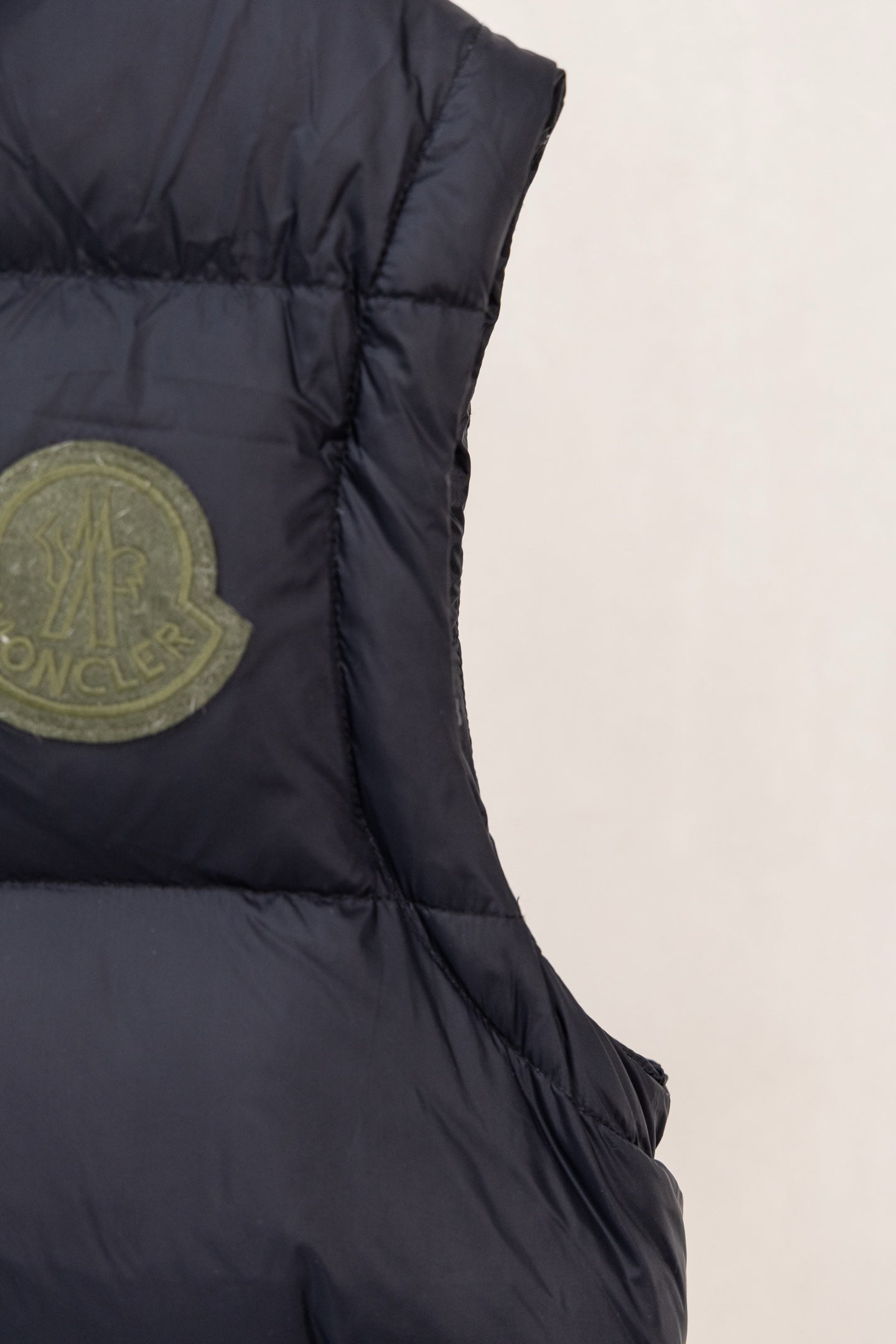 Moncler dark padded vest side seam detail with logo patch