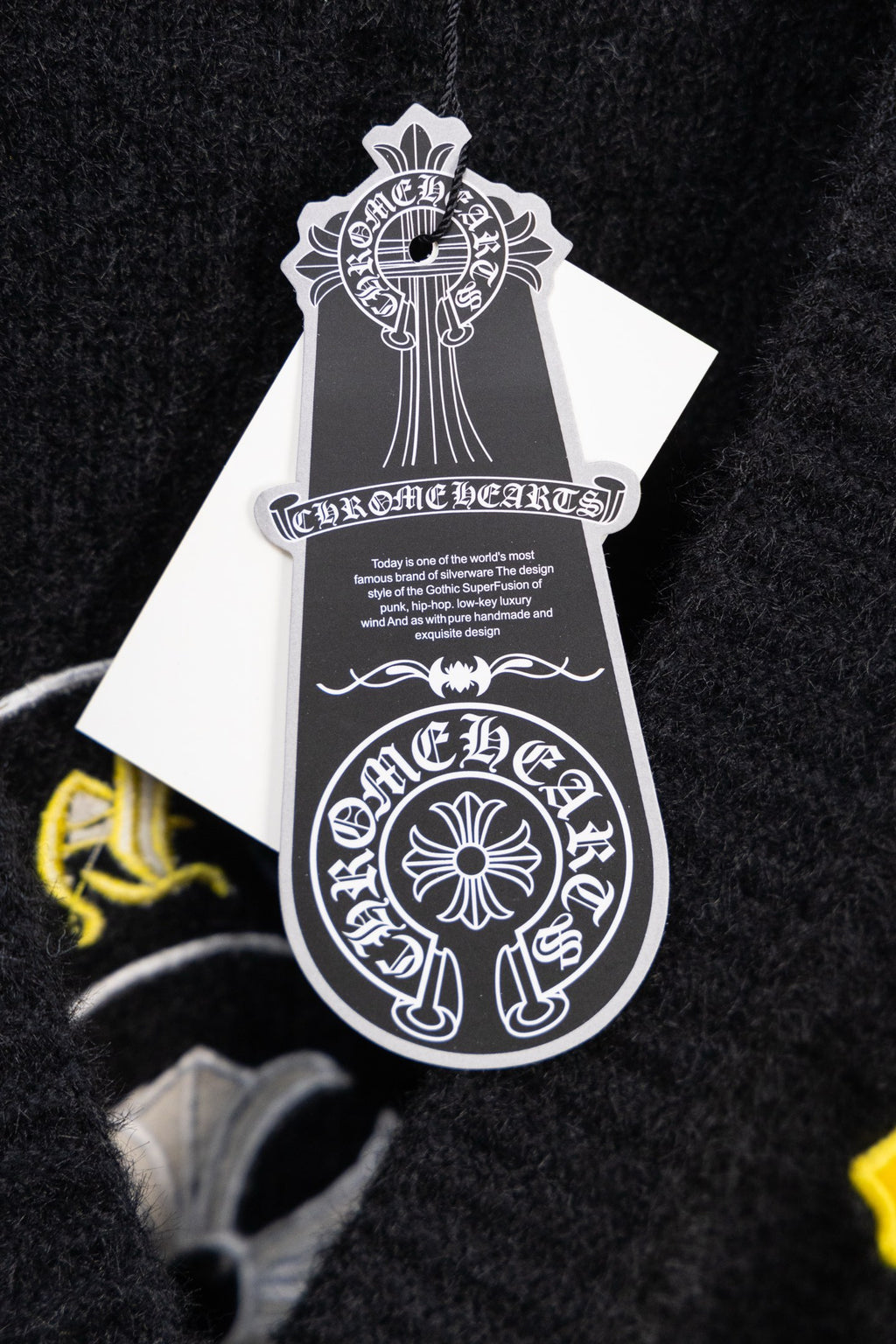 Black cardigan with white hang tag featuring crest-style graphic