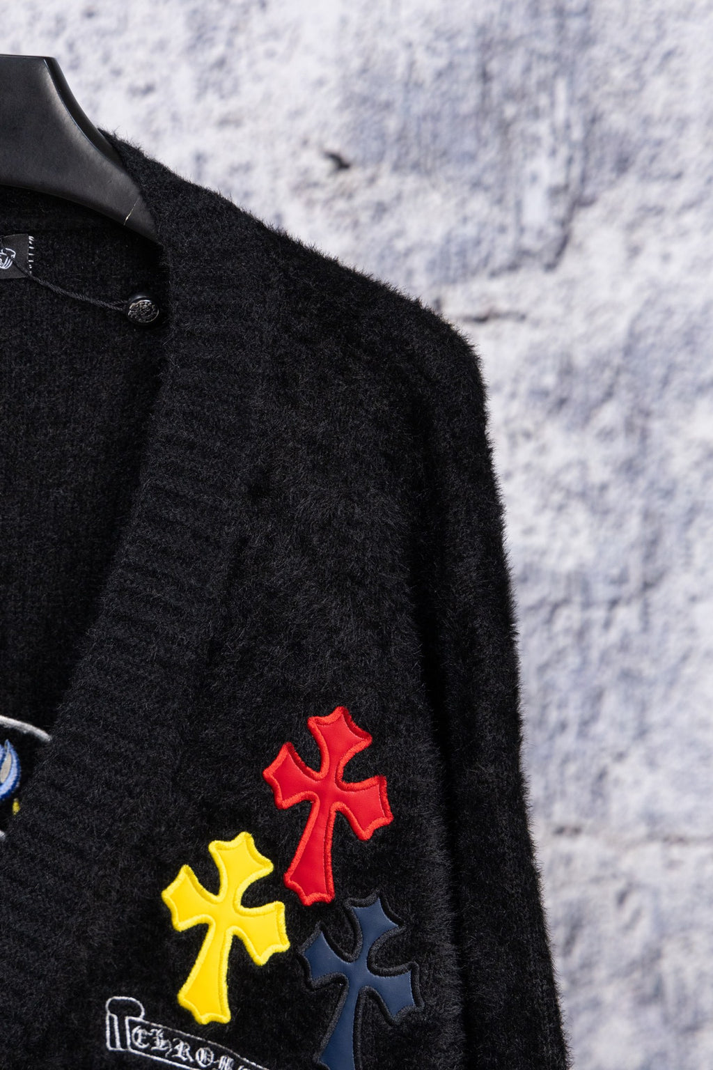 Black cardigan sleeve with red and yellow cross-style embroidered patches
