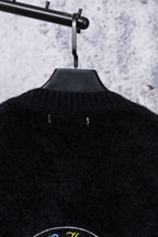Black cardigan back neckline with ribbed texture and small centered emblem