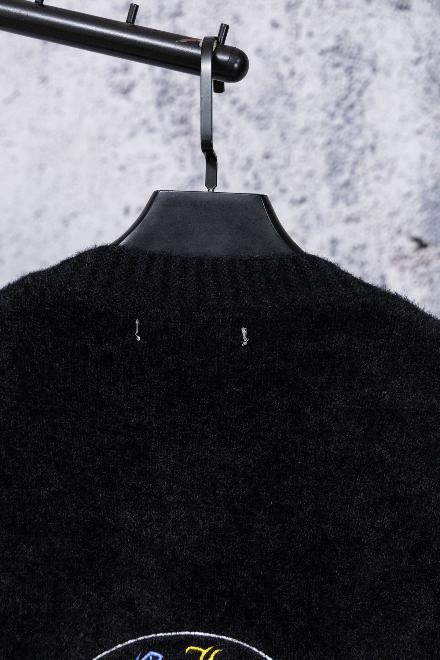 Black cardigan back neckline with ribbed texture and small centered emblem
