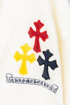 White cardigan sweater close-up of three cross appliques and embroidered banner