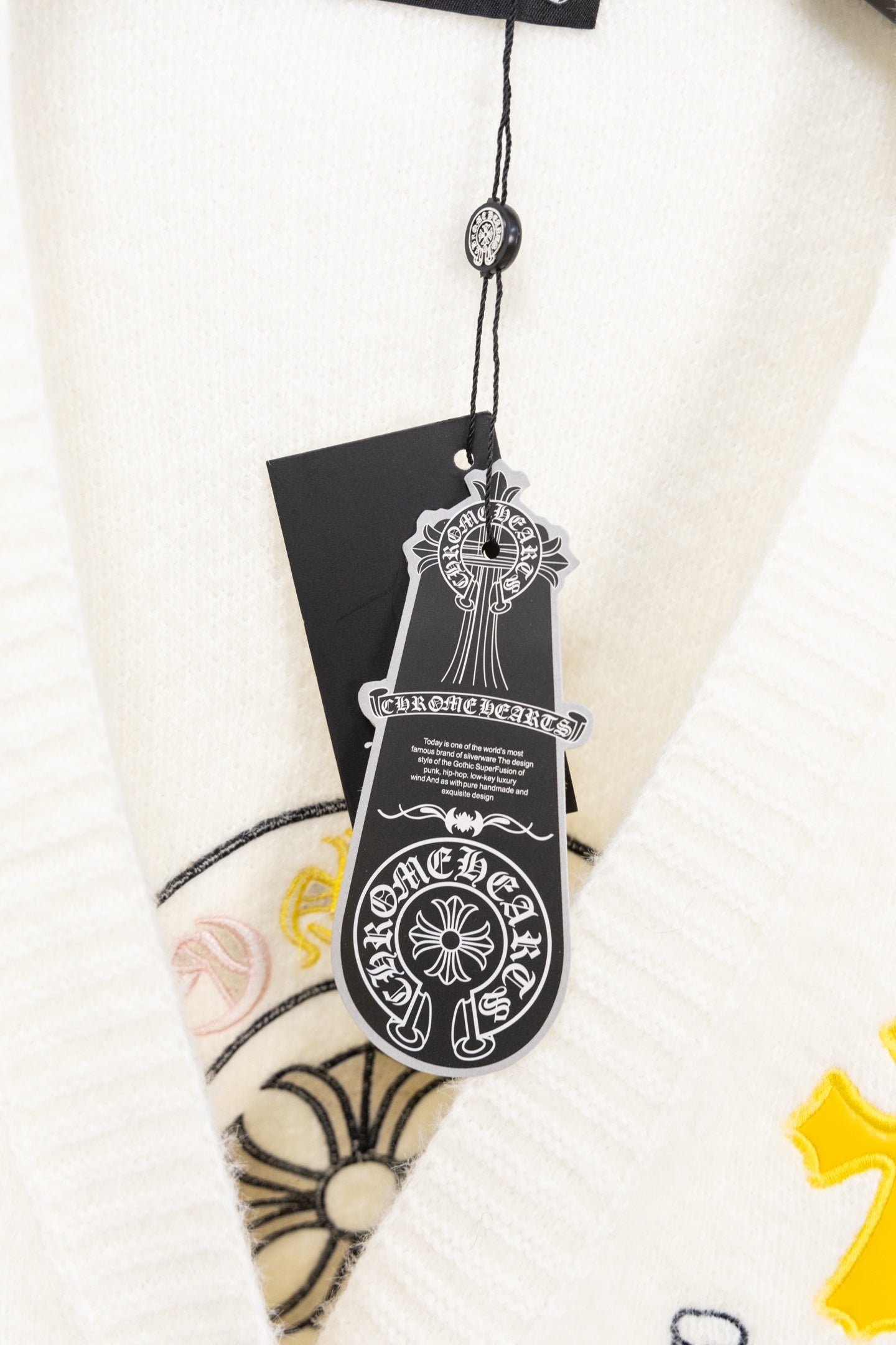White cardigan sweater V-neck detail with black tag and embroidery