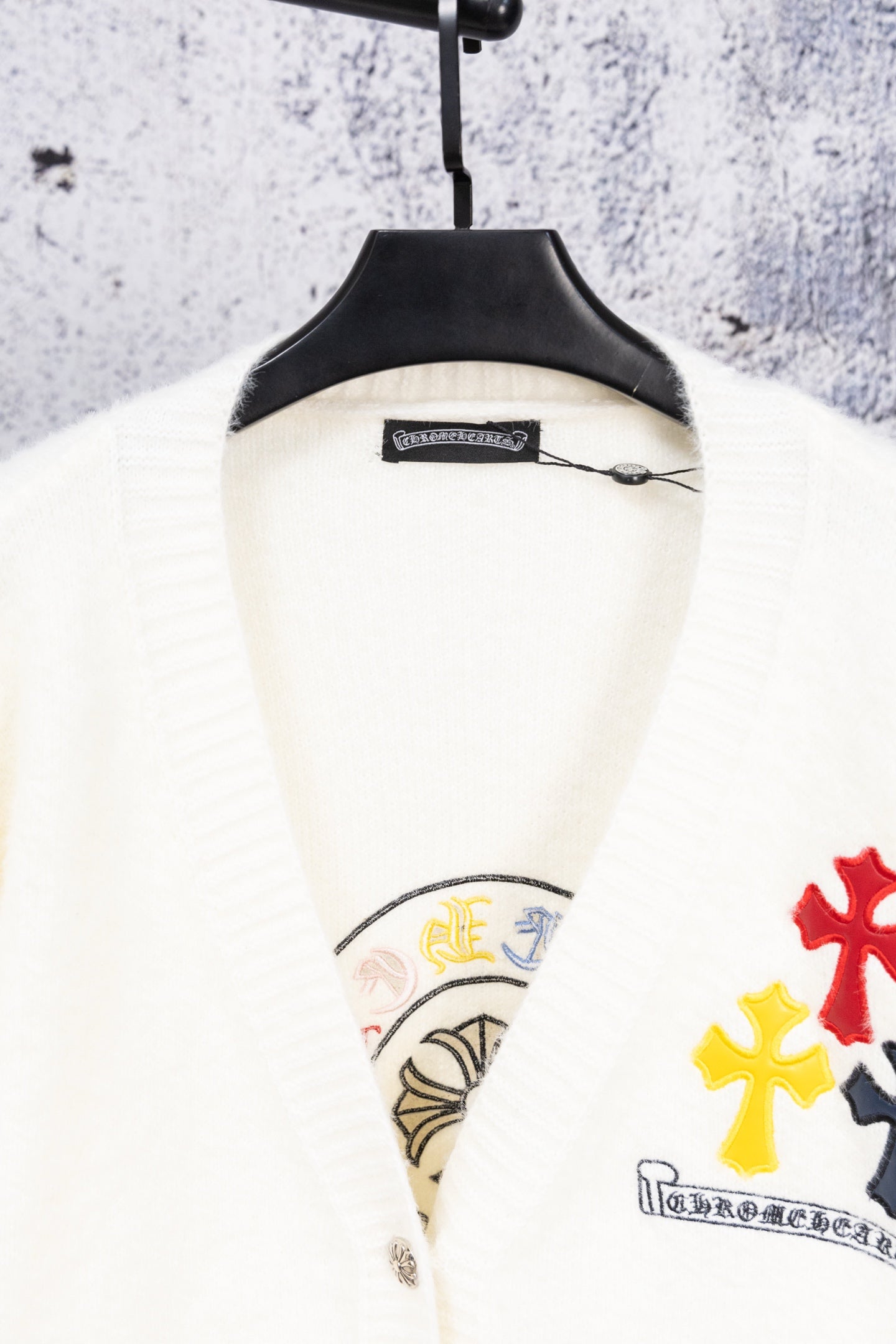 White cardigan sweater close-up of collar and partial embroidered graphic