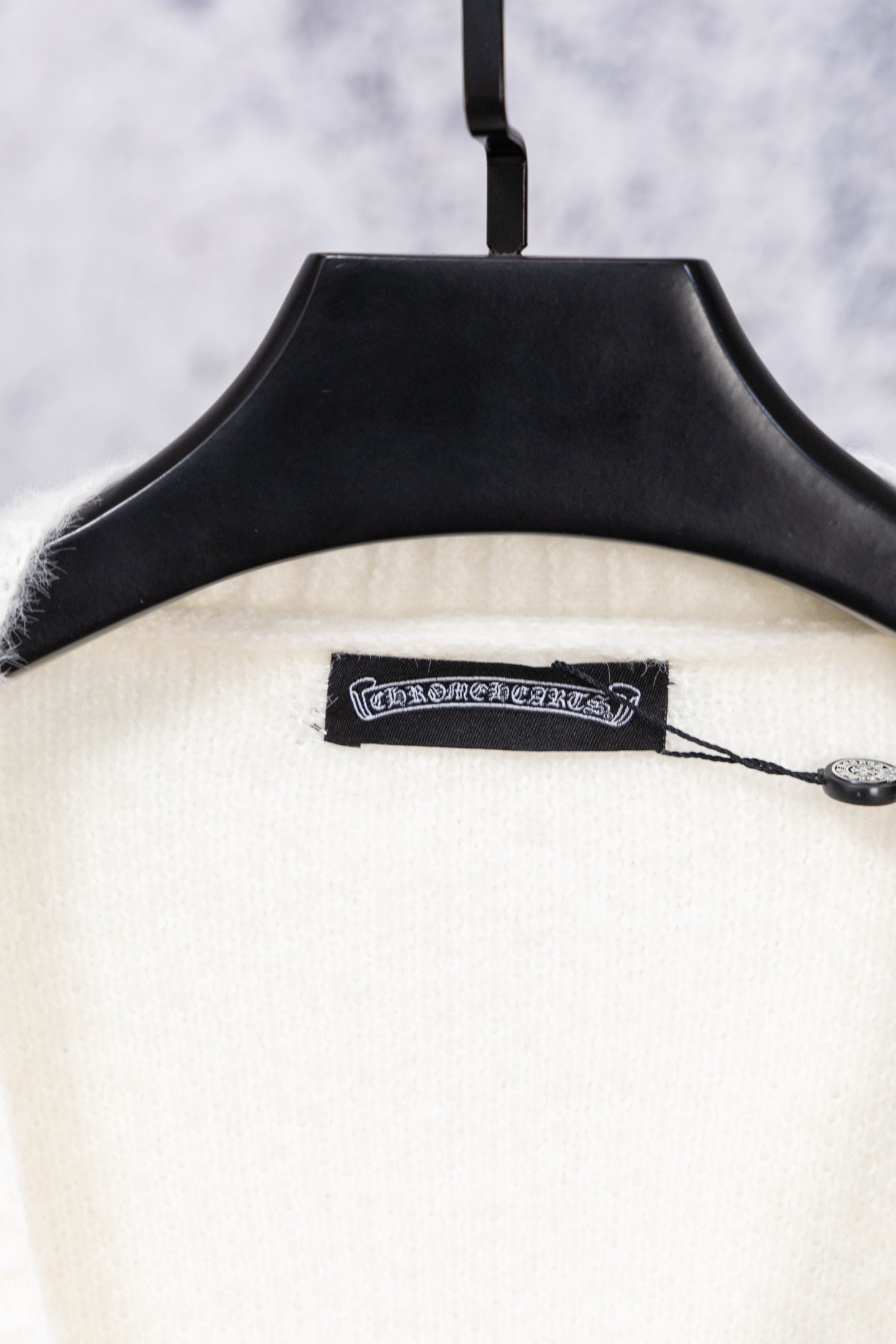 White cardigan sweater neckline label with black trim on hanger