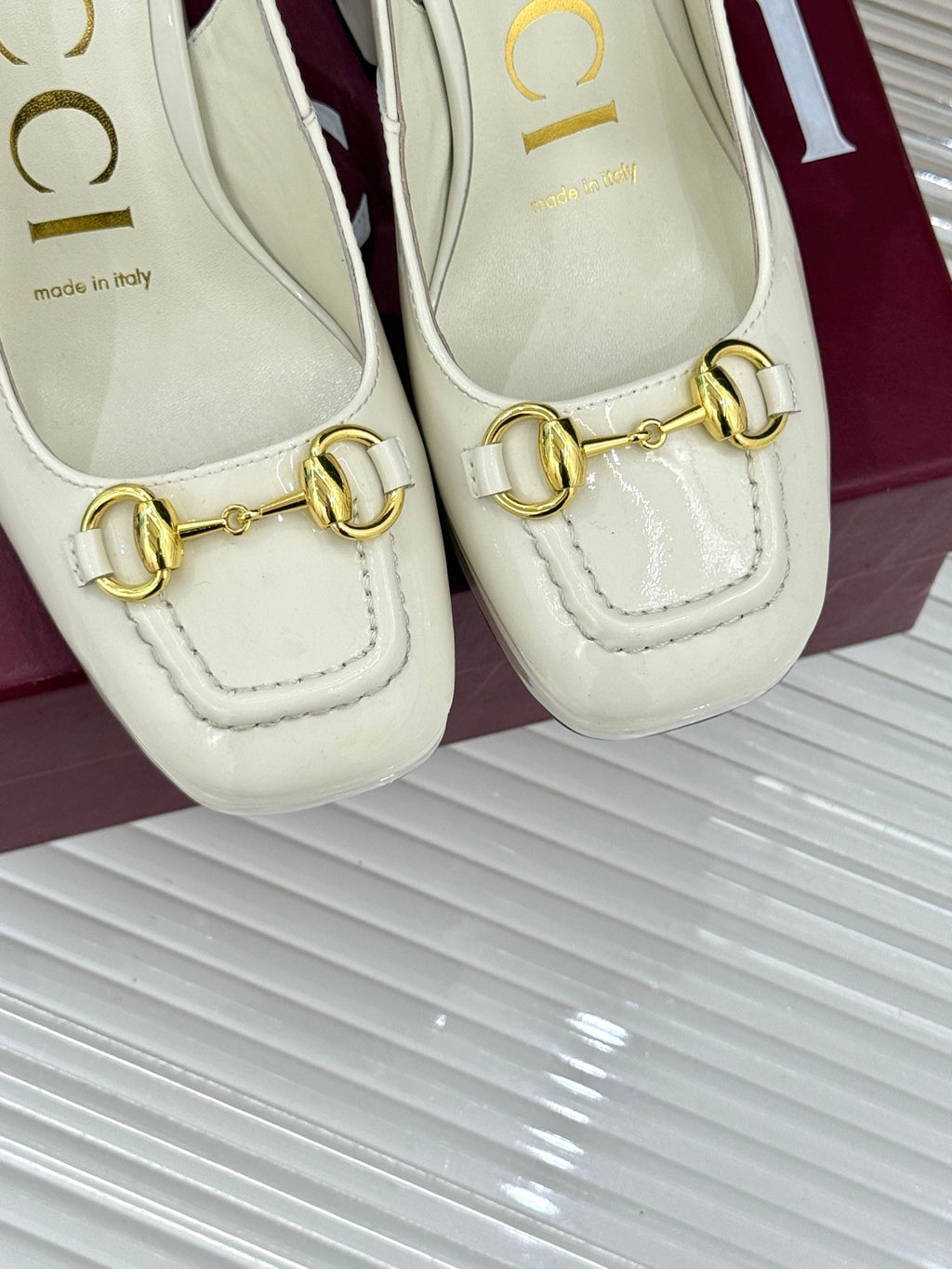 Close-up of cream leather heeled loafers with gold chain hardware detail