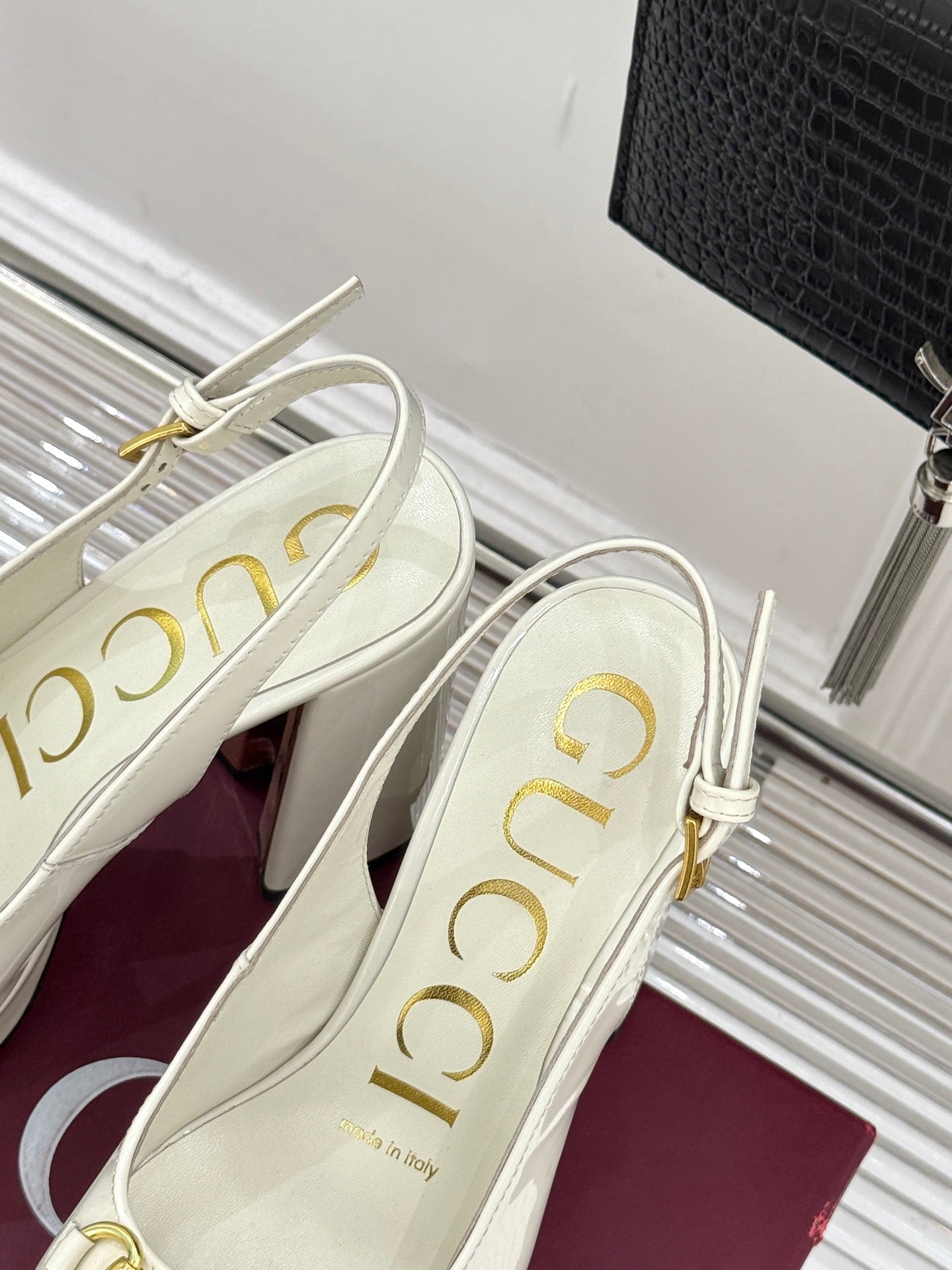 Cream leather heeled loafers with gold buckle chain detail, angled view