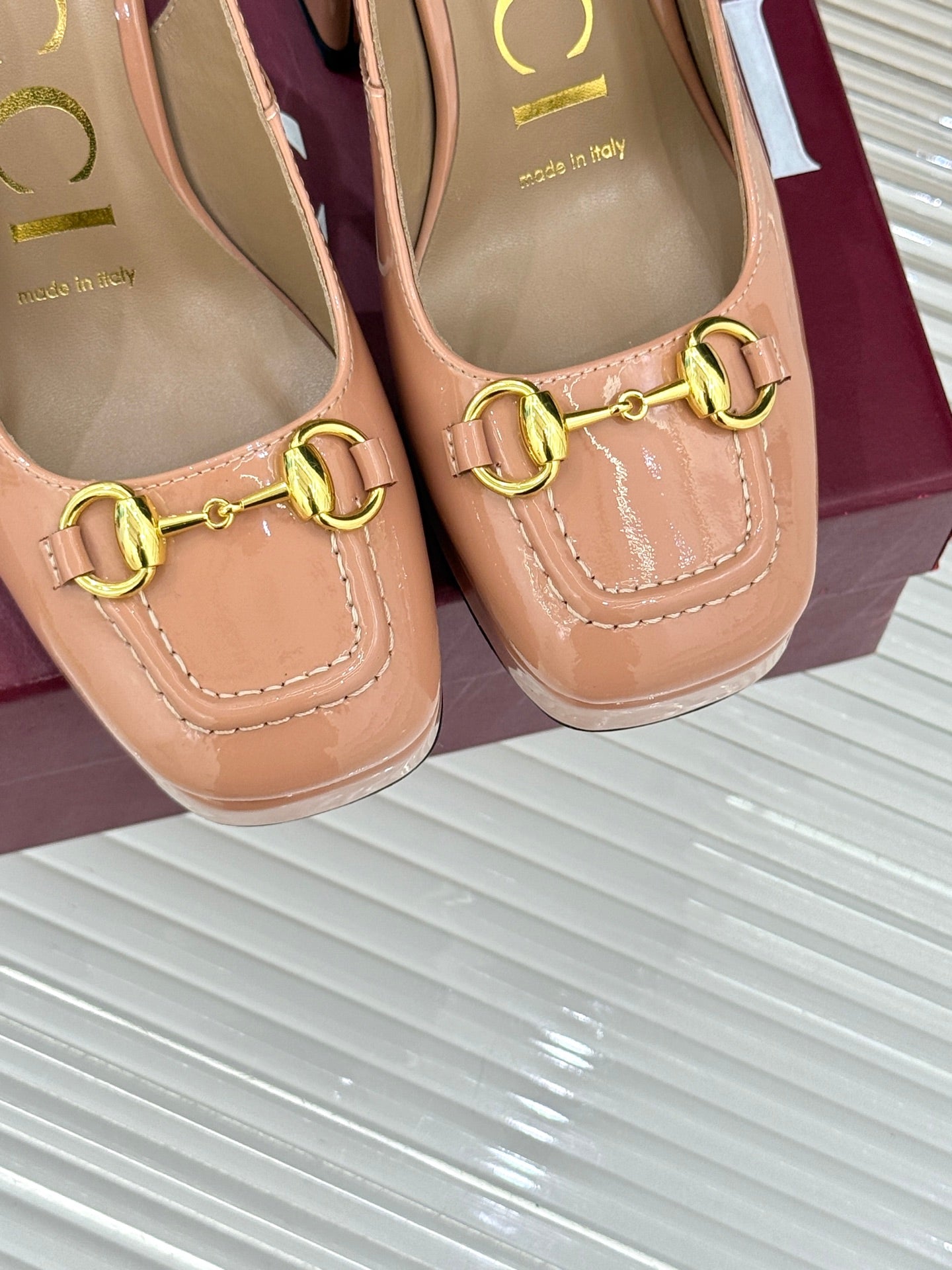 Light pink pumps with gold horsebit buckle and stitched moccasin-style vamp