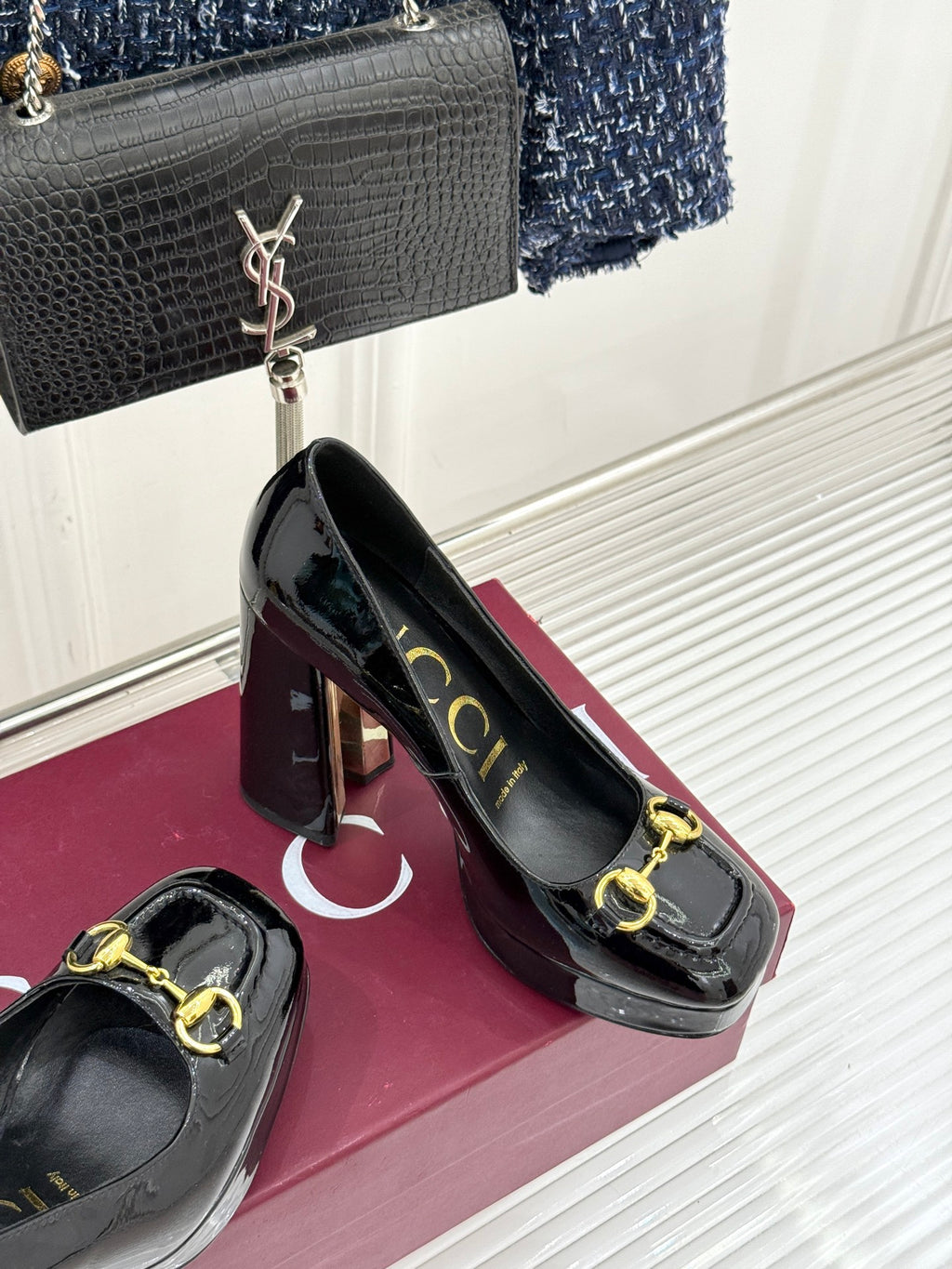 Black patent leather pumps with gold chain horsebit detail on display