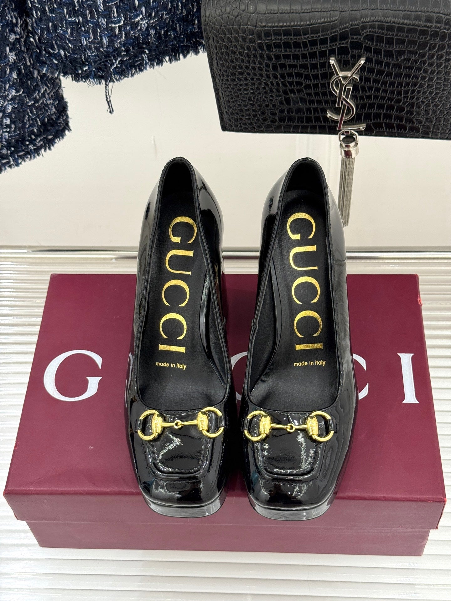 Black patent leather heeled pumps with gold chain horsebit detail, front view
