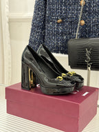 Black patent leather high-heel pumps with gold horsebit detail and round toe