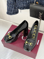 Black patent leather pumps with gold chain horsebit detail, side view