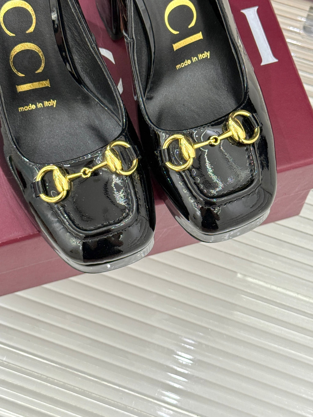 Black patent leather pumps with gold chain horsebit and “made in Italy” text