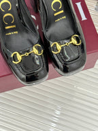 Black patent leather pumps with gold chain horsebit and “made in Italy” text