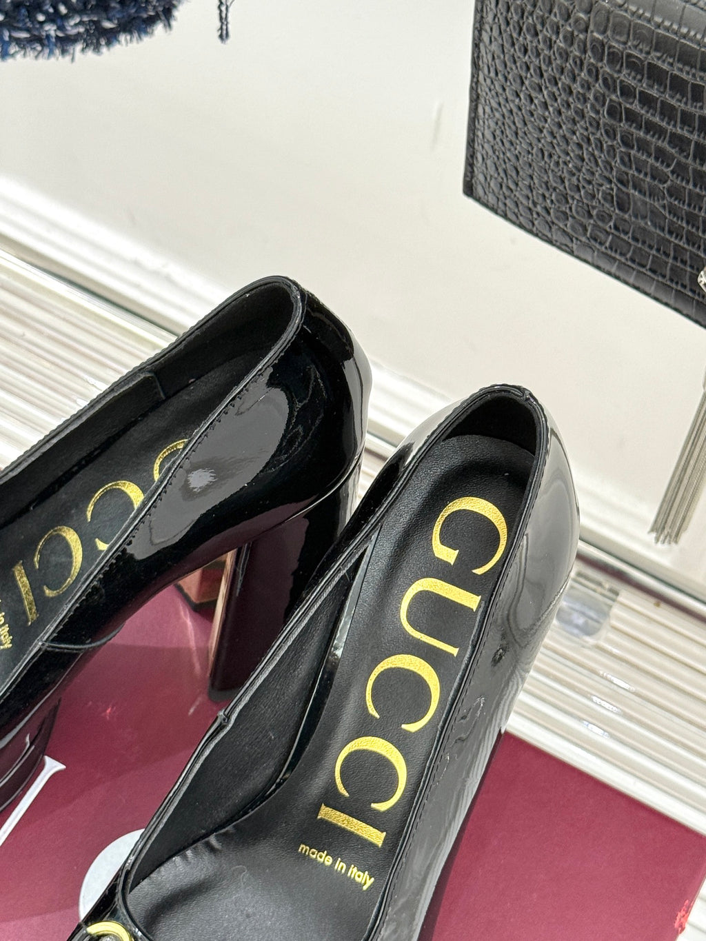 Black patent leather pumps with gold “Gucci” insole lettering, angled view