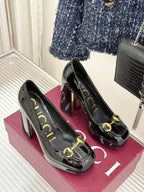 Pair of black patent leather heeled pumps with gold horsebit trim