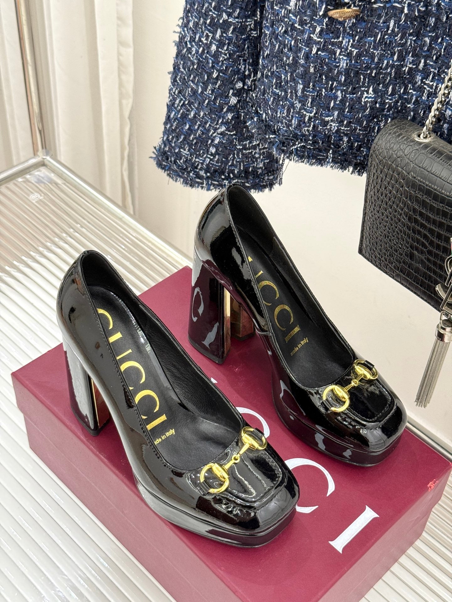 Pair of black patent leather heeled pumps with gold horsebit trim