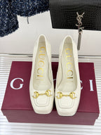 Gucci white leather loafer heels with gold horsebit detail, front view