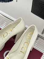 Gucci white leather loafer heels with gold horsebit, angled side view